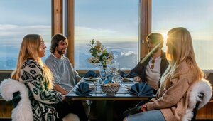 Two couples sitting at a set table in the light of a sunset in the mountains | © Basic Home Production